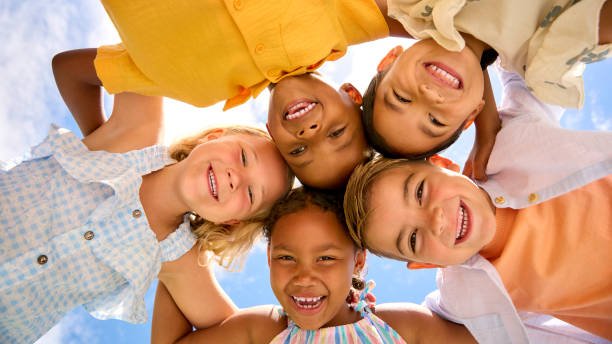 group of multi cultural children friends linking arms looking down into camera